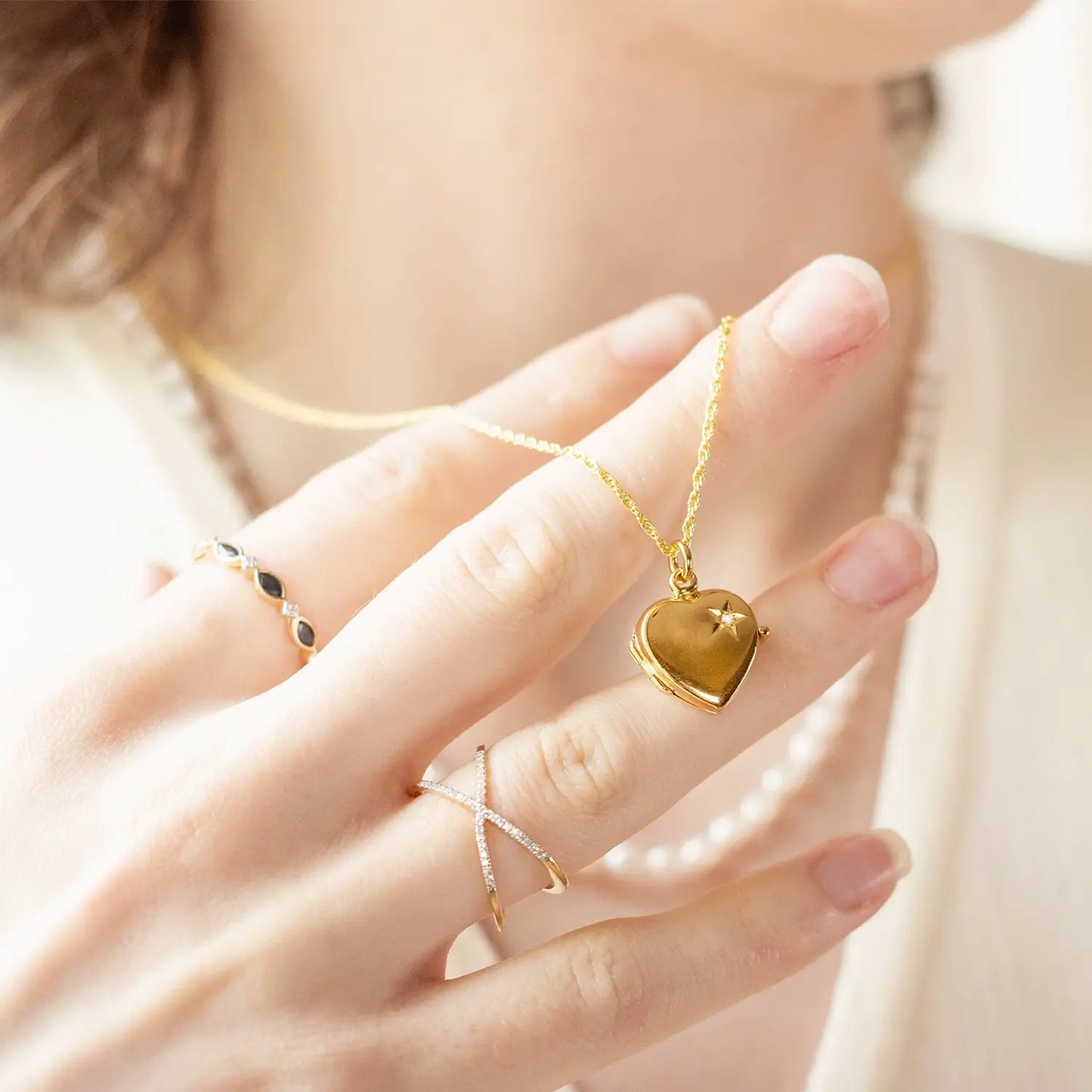 woman holding locket wearing multi diamond cross solid gold ring