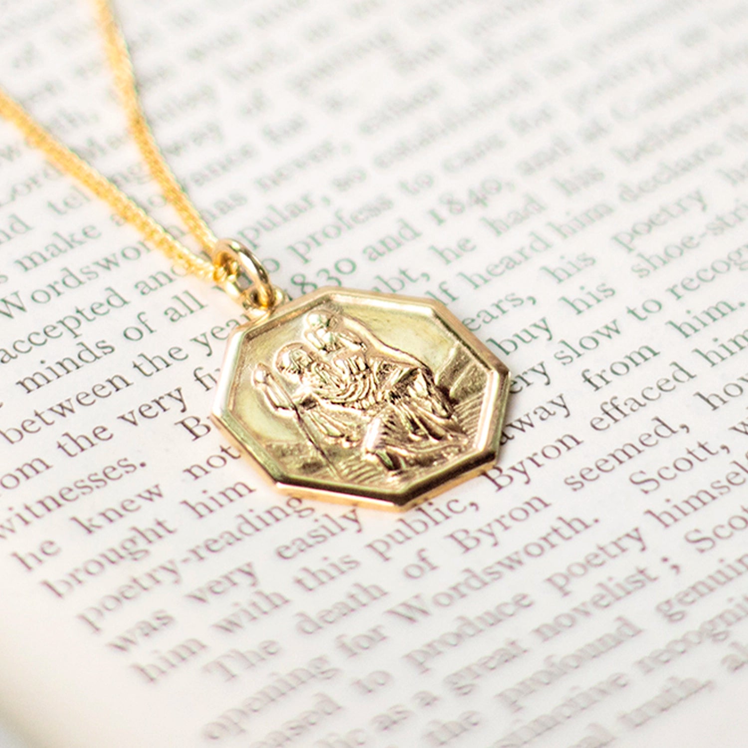 octagonal solid gold st christopher necklace with raised relief on page of book