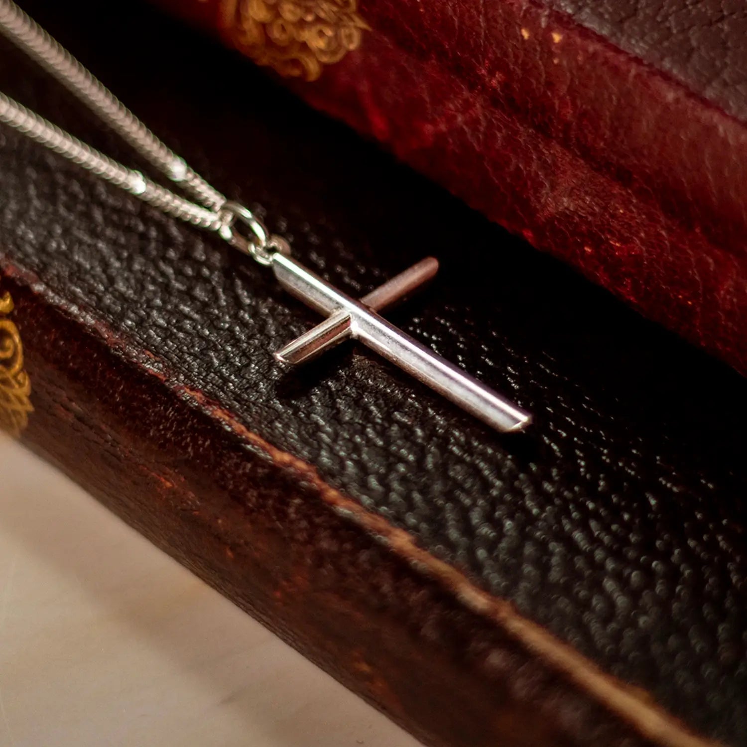 silver cross necklace with chain placed on a book