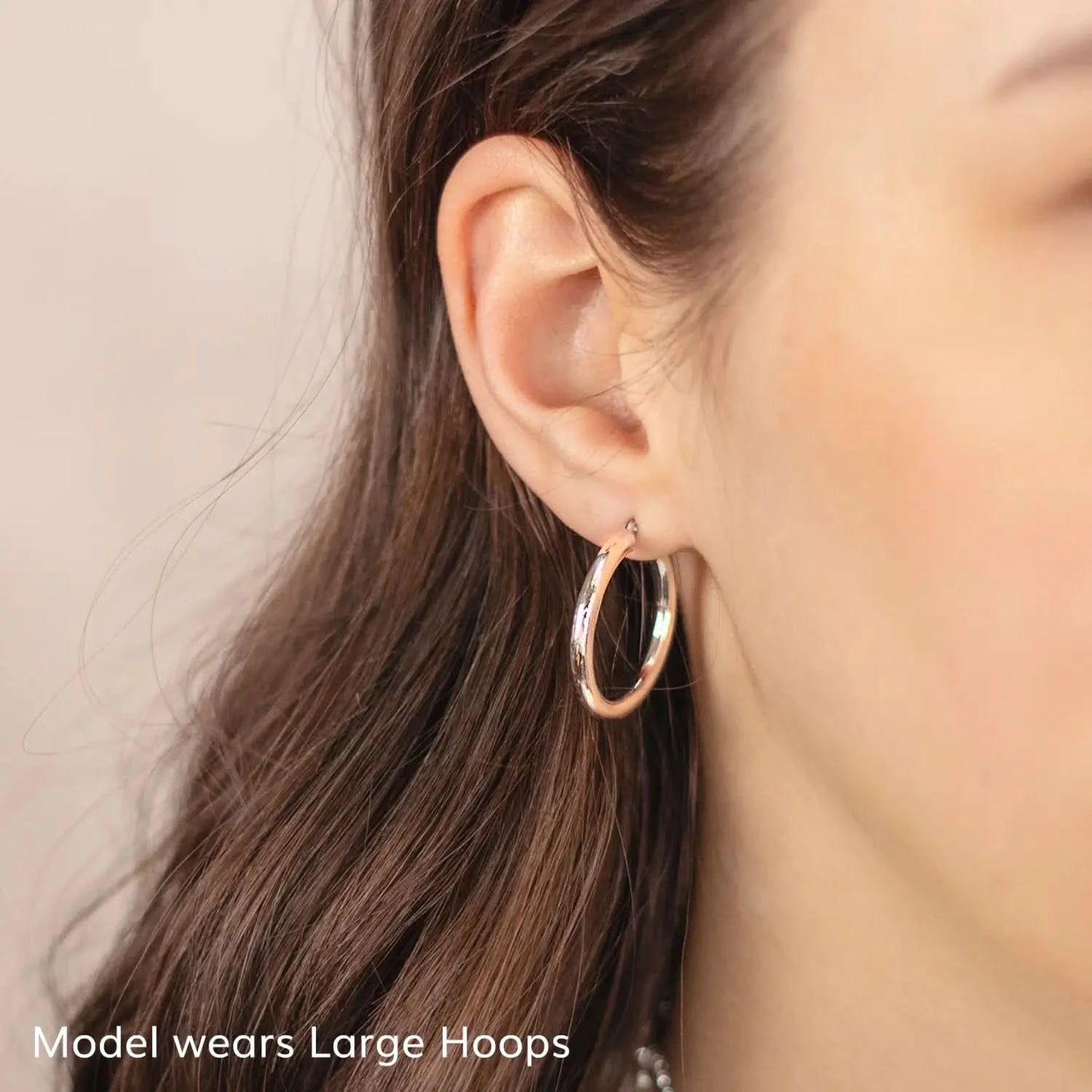 woman wearing chunky white gold hoop earrings, thick round hoop earrings, shiny white gold hoops