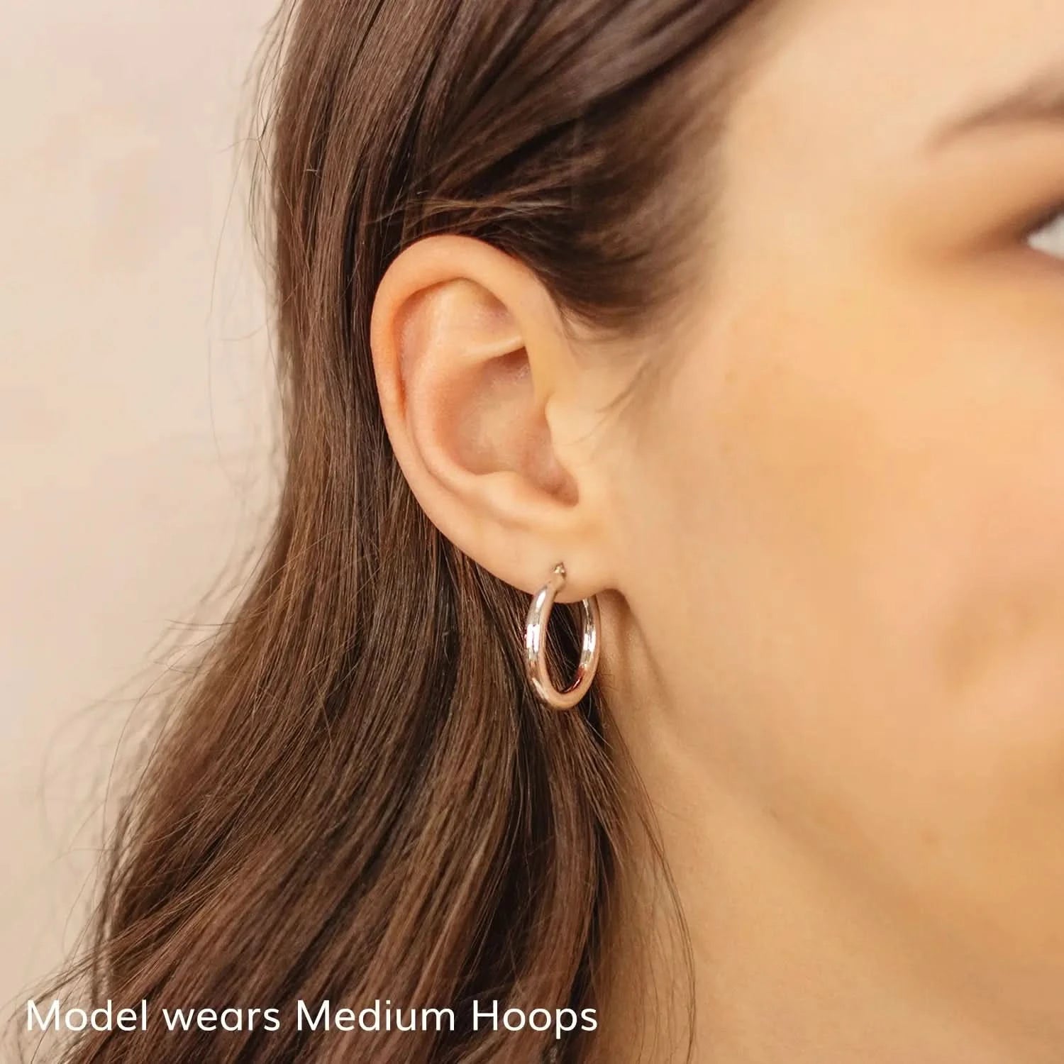 woman wearing chunky white gold hoop earrings, thick round hoop earrings, shiny white gold hoops medium