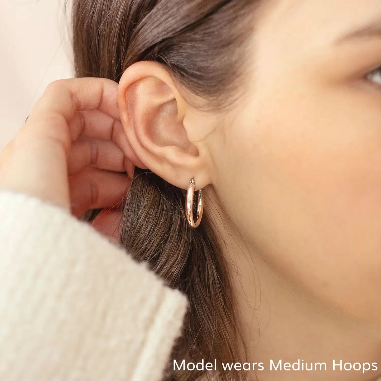 woman wearing chunky white gold hoop earrings, thick round hoop earrings, shiny white gold hoops