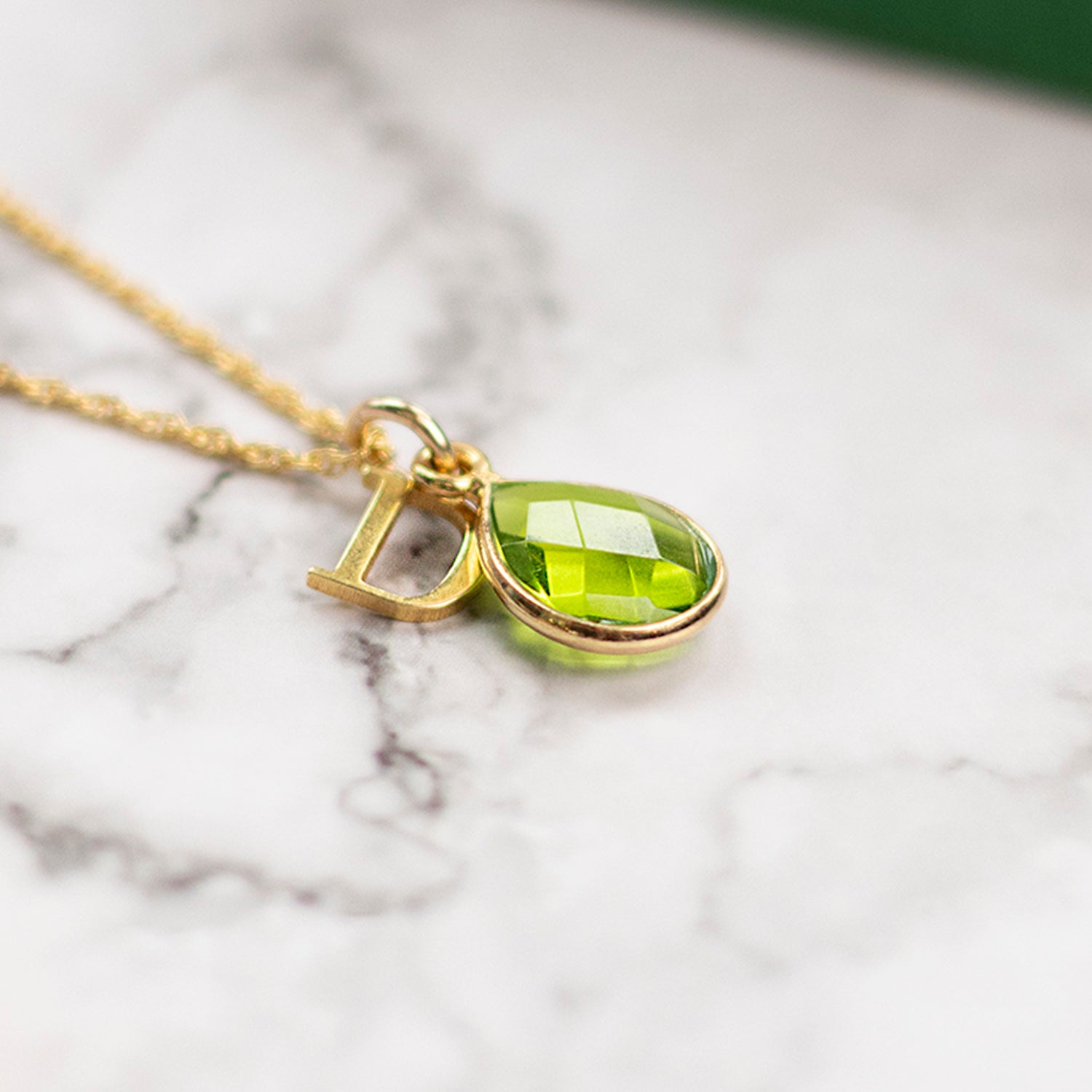 flat lay image of green peridot gold pendant necklace