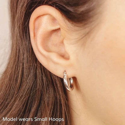 woman wearing chunky white gold hoop earrings, thick round hoop earrings, shiny white gold hoops small